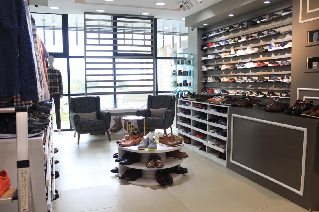 Showroom seating area with two armchairs, a round shoe display and a wall of shoes
